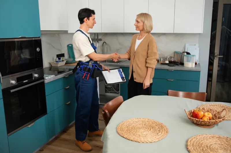 male plumber working with clienst fix kitchen problem