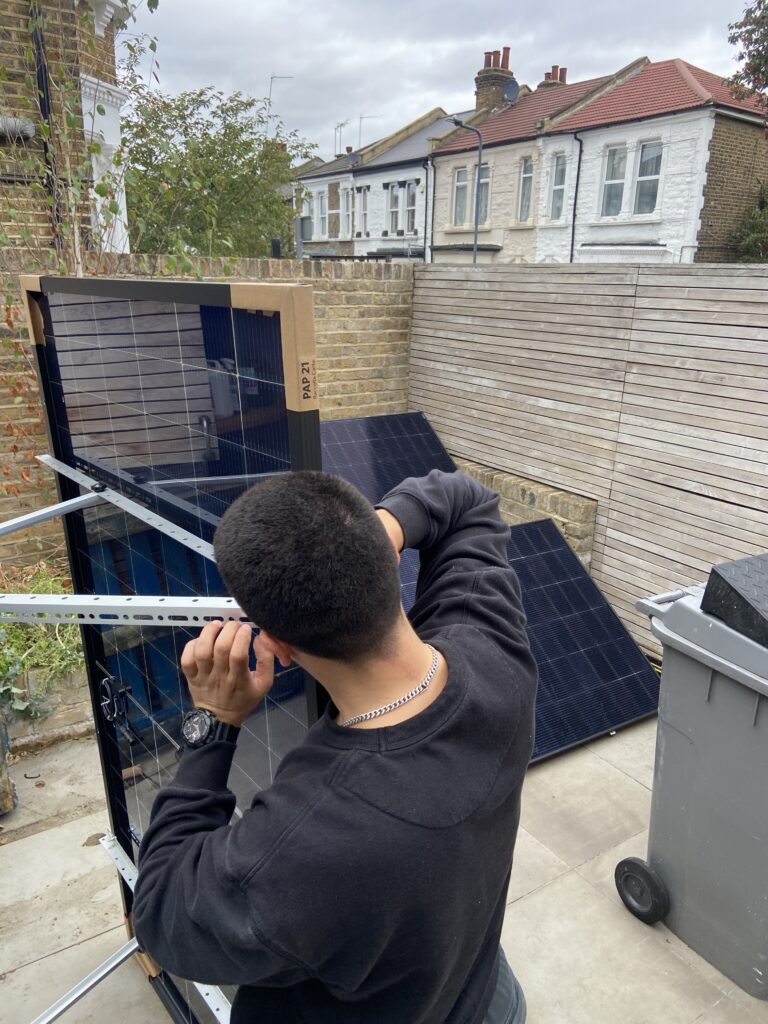 Electrician fitting a solar panel frame for a Victorian terraced house in London