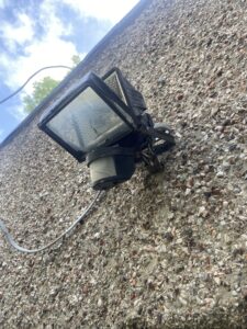 Outdoor floodlight with exposed cable cores found during an EICR in Chiswick