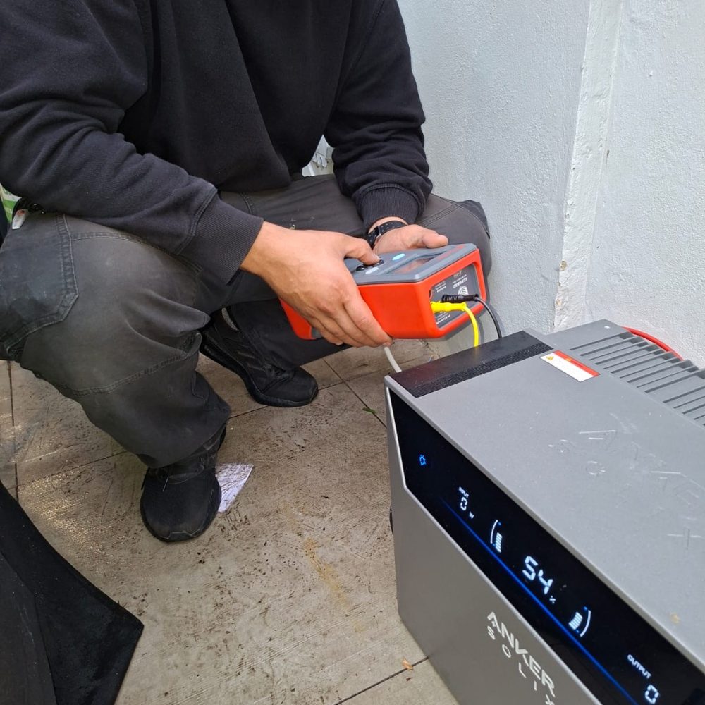 Electrician testing an Anker SOLIX Solarbank 4 E5000 Pro solar battery with a multifunction tester during installation in London
