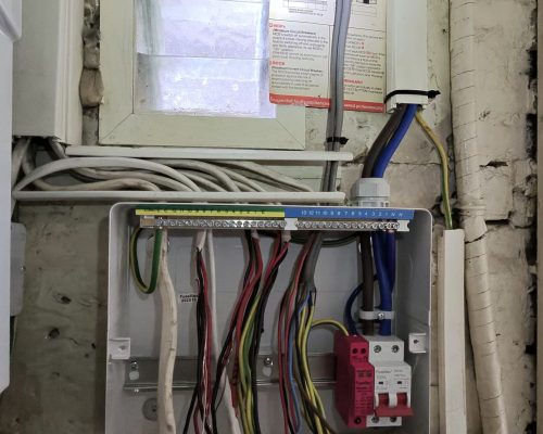 Electrician connecting earth and neutral bars during consumer unit installation in Putney